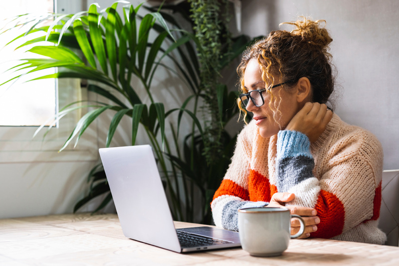 Lady looking at her computer and drinking a coffee